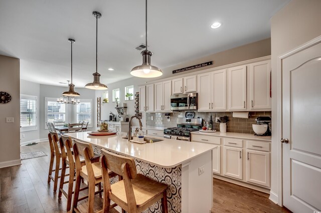 kitchen with stainless steel appliances, a sink, tasteful backsplash, white cabinets, and light countertops