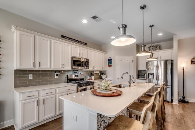kitchen with stainless steel appliances, a sink, white cabinetry, a breakfast bar, and recessed lighting