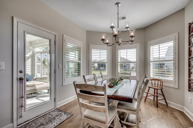 dining area with a chandelier, light wood-style flooring, plenty of natural light, and baseboards