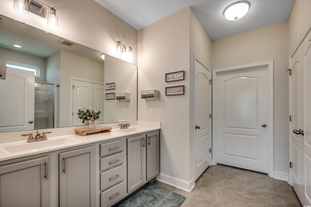 full bathroom featuring a shower stall, tile patterned flooring, baseboards, and double vanity