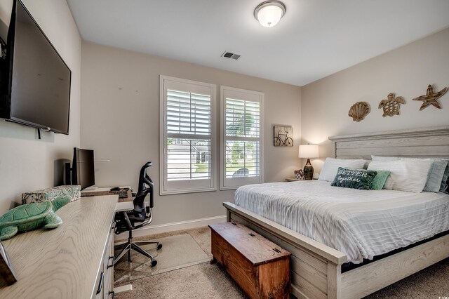 bedroom featuring light carpet, a desk, and baseboards