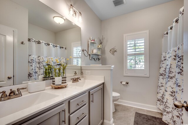 full bathroom with plenty of natural light, toilet, baseboards, and tile patterned flooring