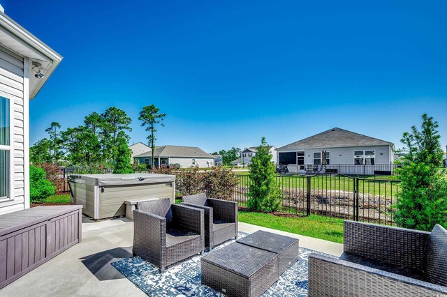 view of patio featuring a hot tub, fence, and a residential view