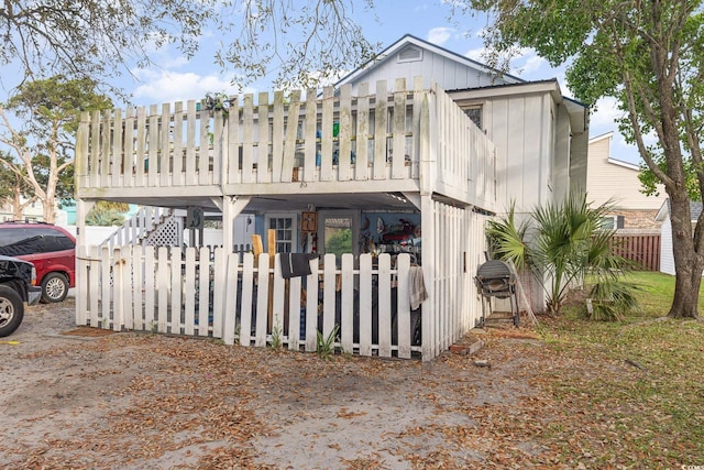 rear view of property featuring stairway, a fenced front yard, and a deck