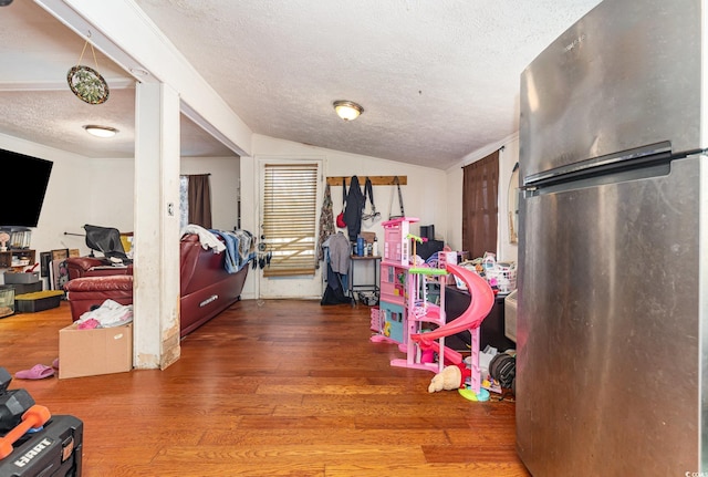 recreation room with wood finished floors, a textured ceiling, and lofted ceiling