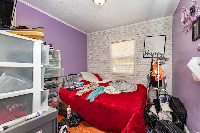 bedroom with a textured ceiling, crown molding, and brick wall