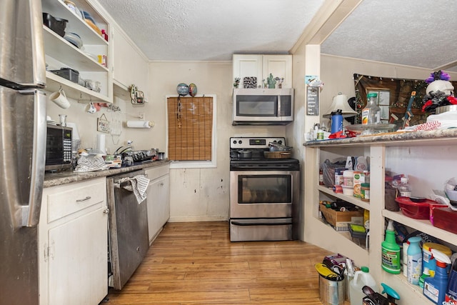 kitchen featuring stainless steel appliances, open shelves, crown molding, light wood-style flooring, and a textured ceiling
