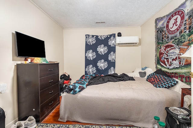 bedroom with a textured ceiling, a wall mounted air conditioner, and visible vents