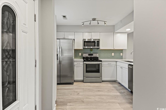 kitchen with a sink, light countertops, light wood-style flooring, stainless steel appliances, and white cabinetry