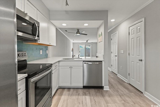 kitchen with a sink, appliances with stainless steel finishes, light wood-style floors, and a ceiling fan