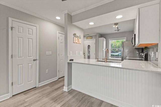 kitchen featuring crown molding, a sink, light wood-style flooring, a peninsula, and recessed lighting