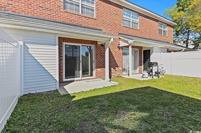 back of property with brick siding, fence, and a yard
