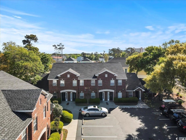 exterior space with a shingled roof and uncovered parking