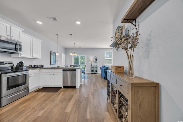 2771 Eclipse Dr, Myrtle Beach, SC 29577 - kitchen with stainless steel appliances, a peninsula, a chandelier, light wood-type flooring, and white cabinets