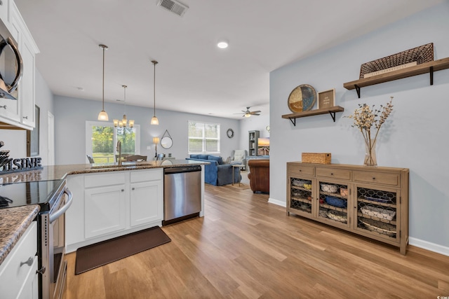 2771 Eclipse Dr, Myrtle Beach, SC 29577 - kitchen with stainless steel appliances, white cabinets, light wood-style floors, a peninsula, and recessed lighting