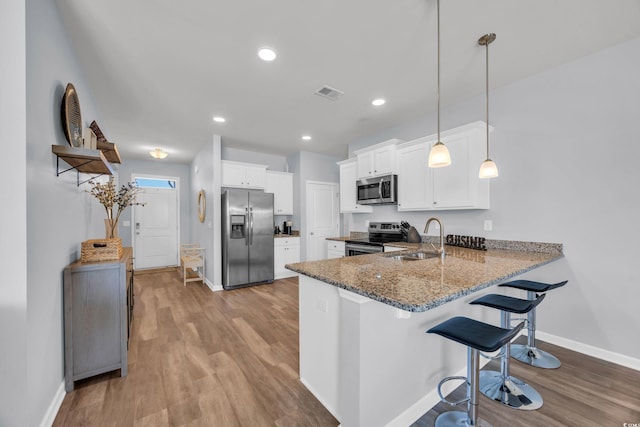 2771 Eclipse Dr, Myrtle Beach, SC 29577 - kitchen featuring stainless steel appliances, dark stone counters, a kitchen breakfast bar, a peninsula, and wood finished floors