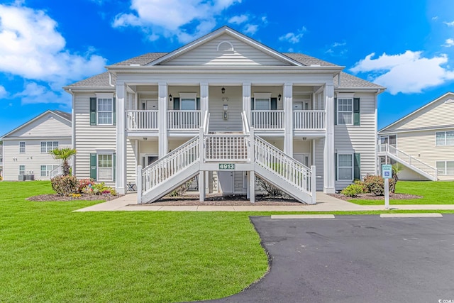 exterior space with stairs, a front lawn, roof with shingles, and a porch