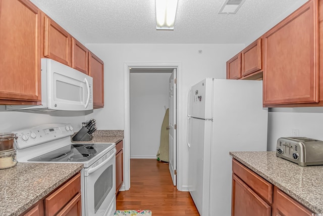 kitchen with white appliances, a textured ceiling, wood finished floors, a toaster, and visible vents