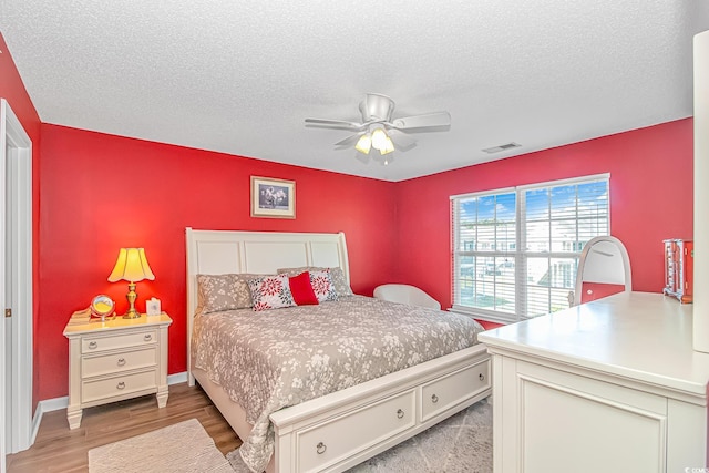 bedroom featuring ceiling fan, light wood-type flooring, a textured ceiling, and visible vents