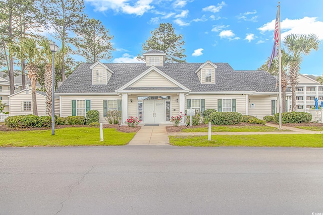 view of front facade featuring roof with shingles and a front yard
