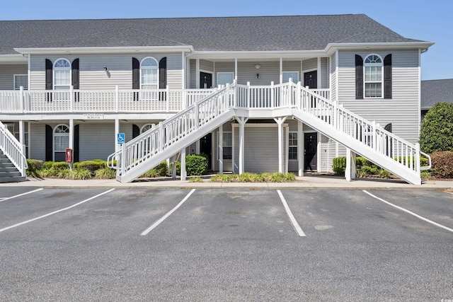 view of building exterior with stairs and uncovered parking