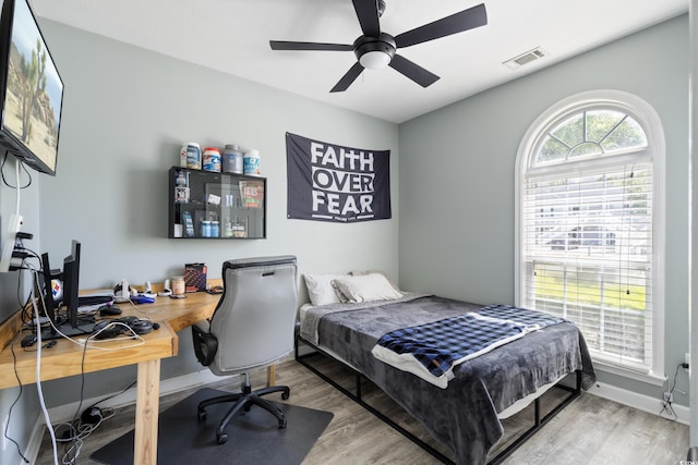 bedroom with baseboards, a ceiling fan, wood finished floors, and visible vents