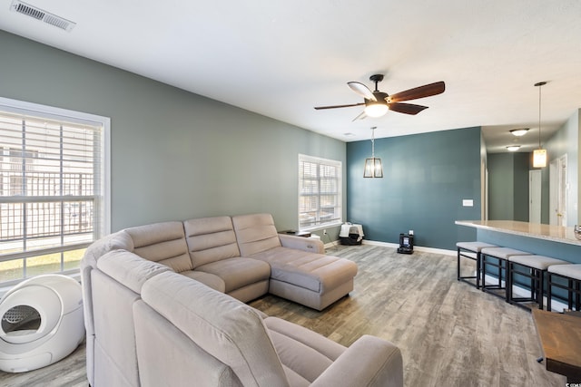 living area featuring ceiling fan, baseboards, wood finished floors, and visible vents
