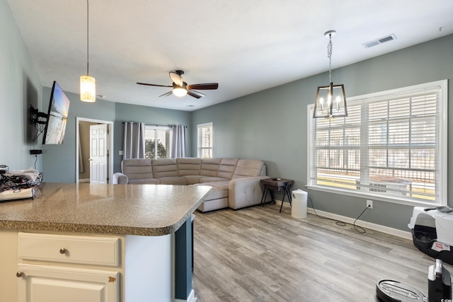 kitchen featuring pendant lighting, light wood-style floors, visible vents, and ceiling fan with notable chandelier