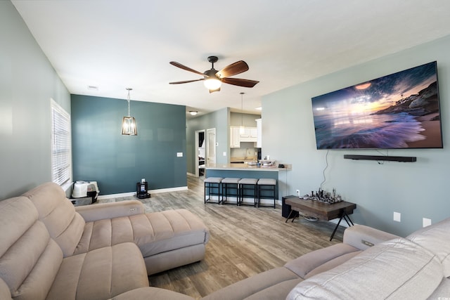 living room featuring wood finished floors, baseboards, and ceiling fan