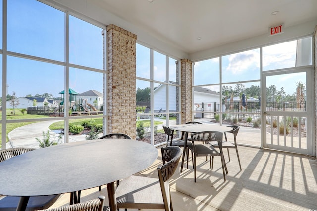 sunroom / solarium featuring outdoor dining area, plenty of natural light, and a residential view