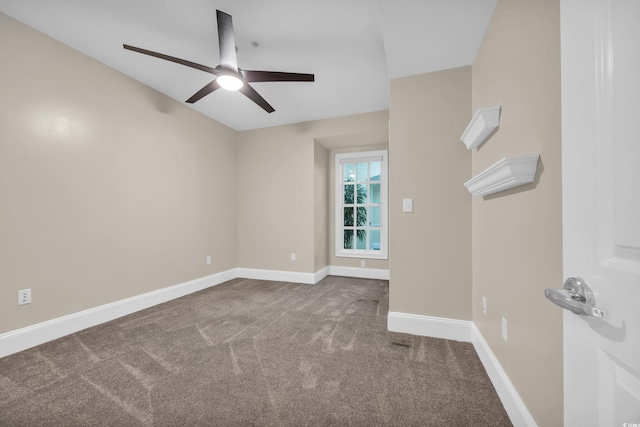 carpeted spare room featuring a ceiling fan and baseboards