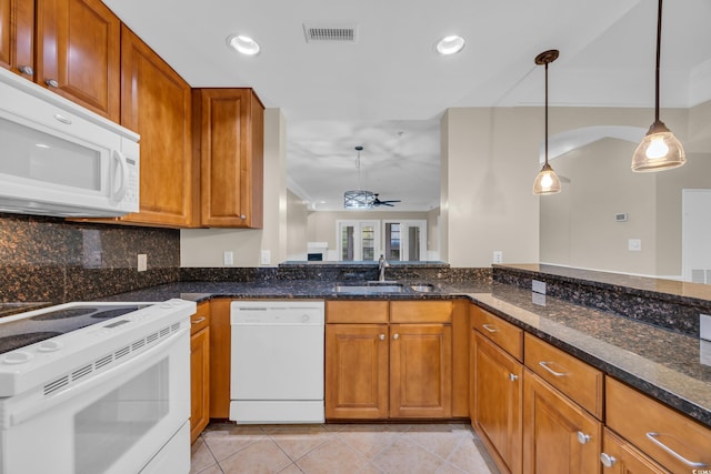 kitchen featuring visible vents, a sink, white appliances, brown cabinetry, and hanging light fixtures