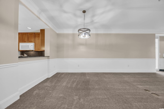 unfurnished dining area featuring dark carpet and ornamental molding