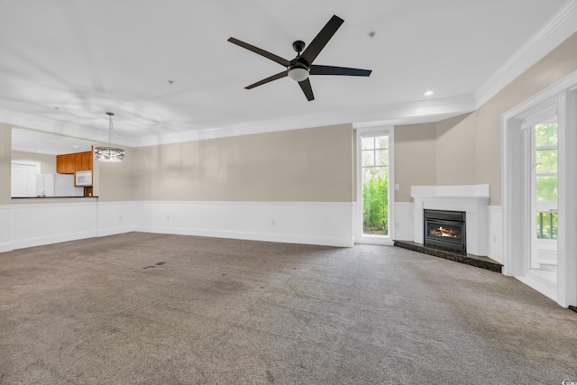 unfurnished living room featuring wainscoting, carpet flooring, a glass covered fireplace, and ornamental molding