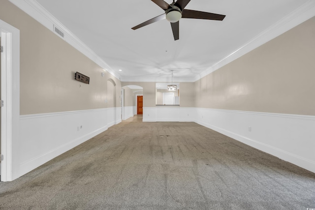 carpeted empty room featuring arched walkways, visible vents, ornamental molding, and ceiling fan