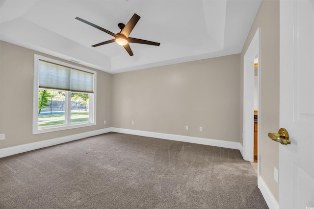 unfurnished room featuring ceiling fan, baseboards, carpet flooring, and a tray ceiling