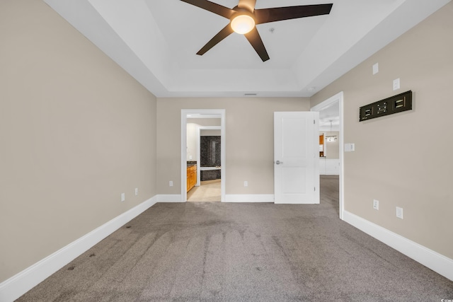 unfurnished bedroom with carpet flooring, baseboards, a ceiling fan, connected bathroom, and a raised ceiling