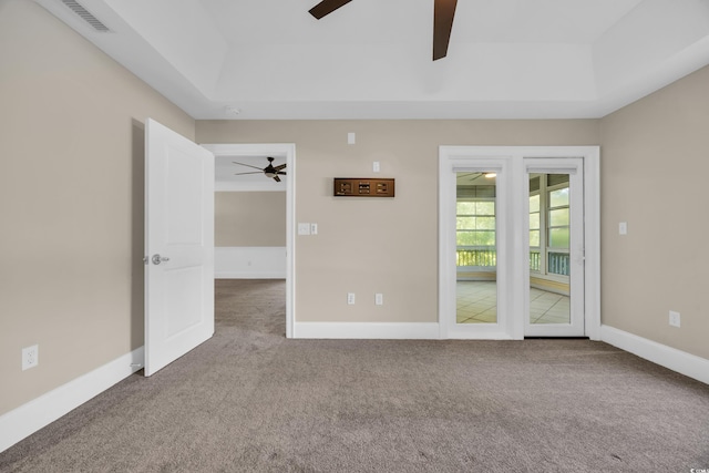 carpeted spare room featuring ceiling fan, baseboards, visible vents, and a raised ceiling