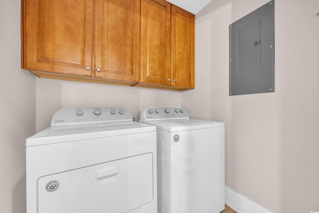 clothes washing area featuring cabinet space, electric panel, and washer and dryer