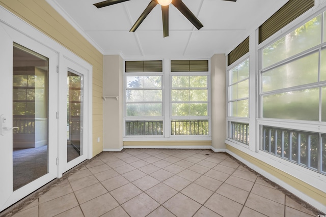 unfurnished sunroom featuring baseboards, a ceiling fan, and tile patterned floors
