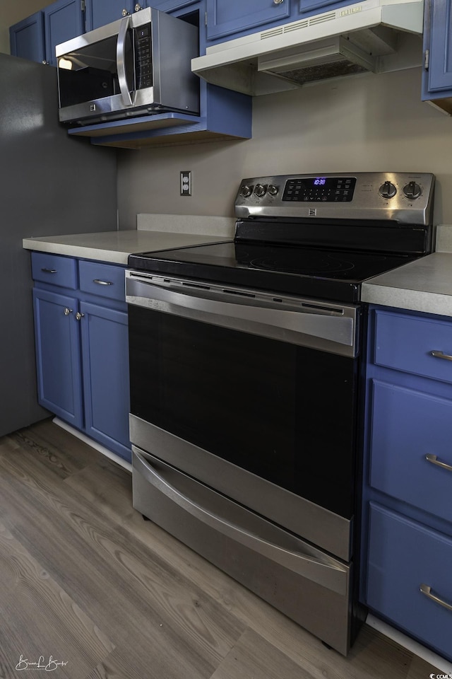 409 5th Ave S Unit 409, Surfside Beach, SC 29575 - kitchen featuring blue cabinetry, appliances with stainless steel finishes, and wood finished floors