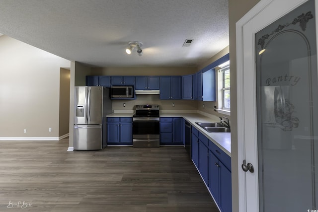 409 5th Ave S Unit 409, Surfside Beach, SC 29575 - kitchen with stainless steel appliances, a sink, blue cabinetry, under cabinet range hood, and light countertops
