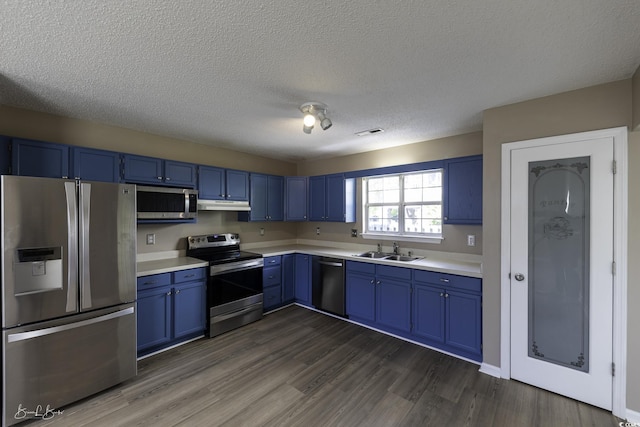 409 5th Ave S Unit 409, Surfside Beach, SC 29575 - kitchen featuring appliances with stainless steel finishes, blue cabinets, a sink, under cabinet range hood, and light countertops