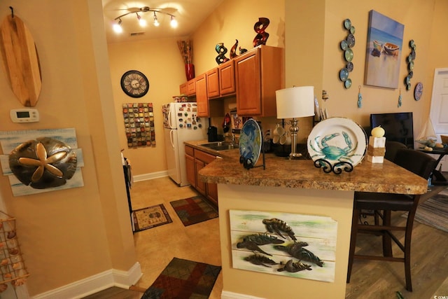 110 Portsmith Dr Unit 8, Myrtle Beach, SC 29588 - kitchen with freestanding refrigerator, a kitchen breakfast bar, baseboards, brown cabinetry, and a peninsula