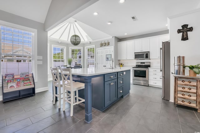kitchen featuring appliances with stainless steel finishes, light countertops, a sink, white cabinets, and lofted ceiling