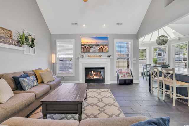 living area with recessed lighting, high vaulted ceiling, a glass covered fireplace, and visible vents