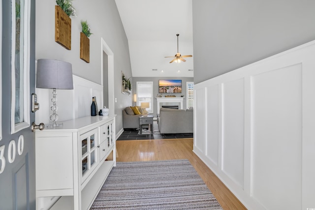 hallway featuring light wood-style floors and high vaulted ceiling