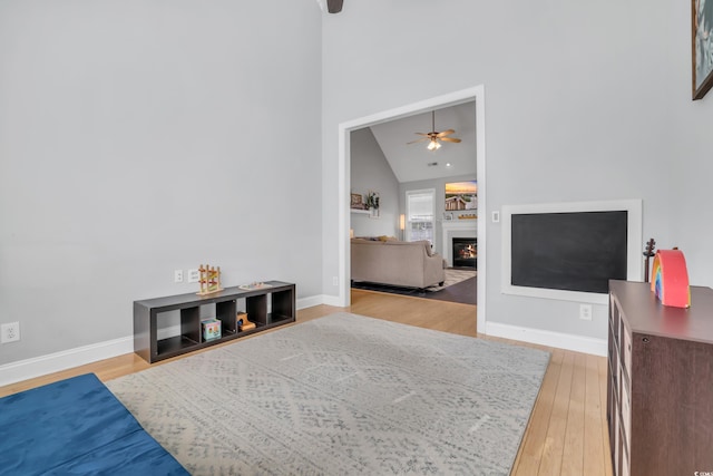 living area with light wood-style floors, a ceiling fan, and baseboards