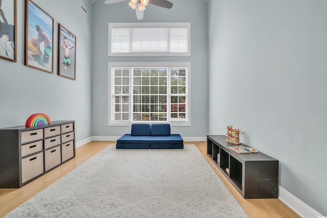 sitting room featuring baseboards, ceiling fan, light wood-type flooring, and visible vents