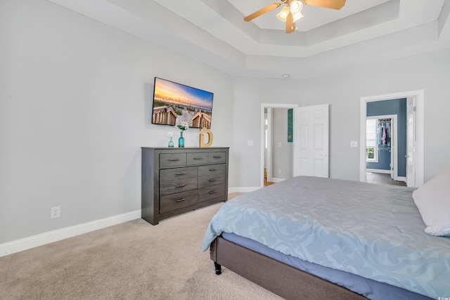 bedroom with a raised ceiling, a ceiling fan, baseboards, and carpet